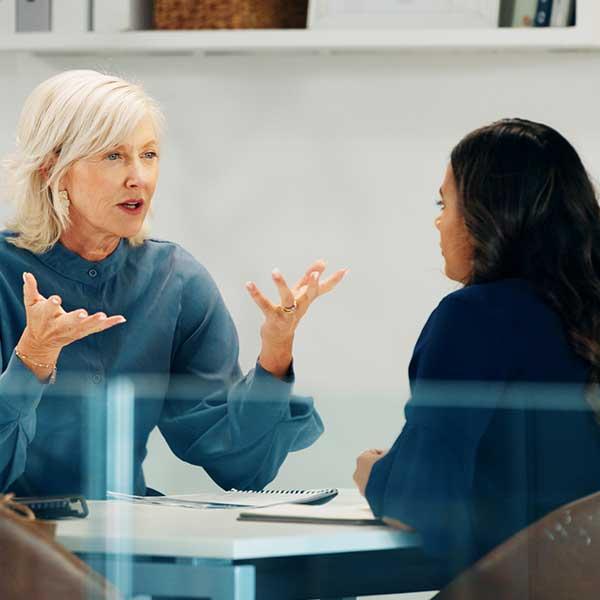 Meeting between two female workers in an office location.